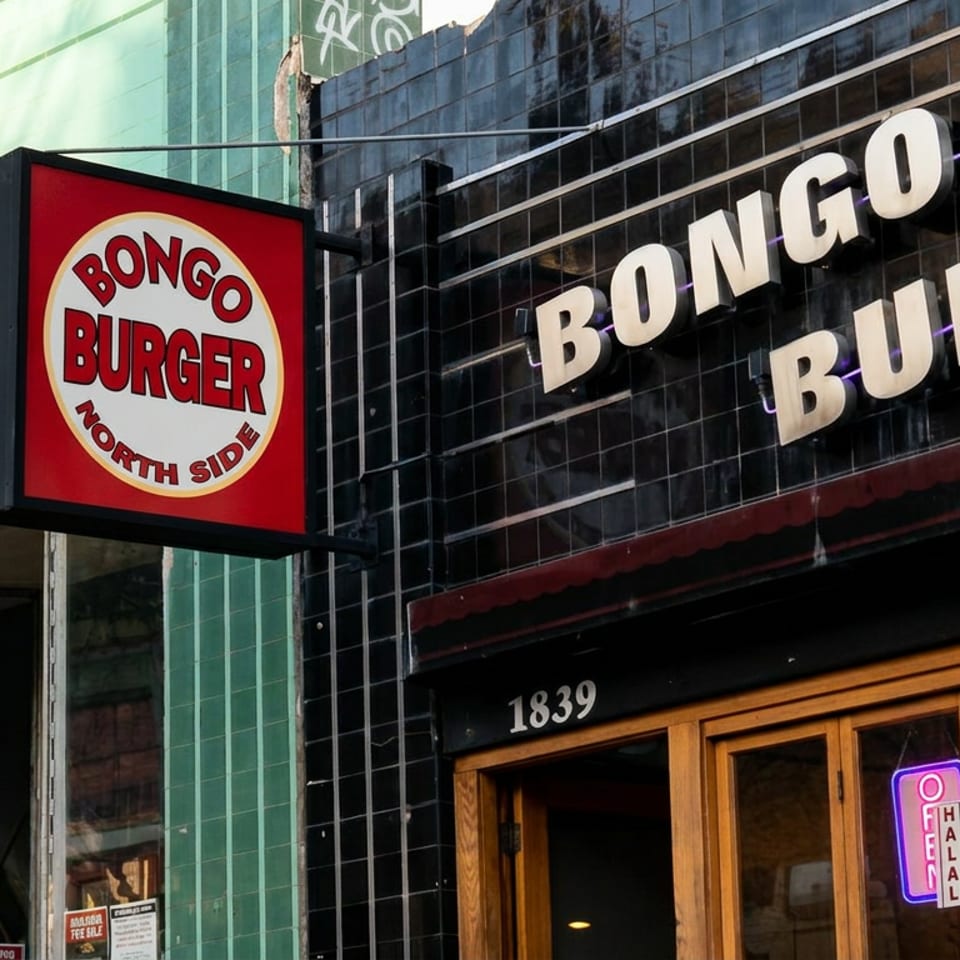 Street-facing entrance of Bongo Burger North Side, featuring bold signage, tiled facade, wooden doors, and neon window lights.